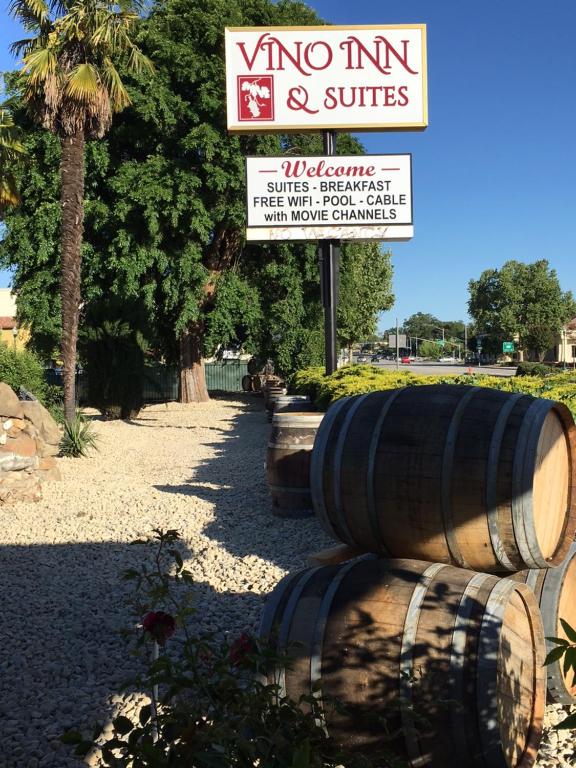 a sign for a vineyard and suites with two barrels at Vino Inn & Suites in Atascadero