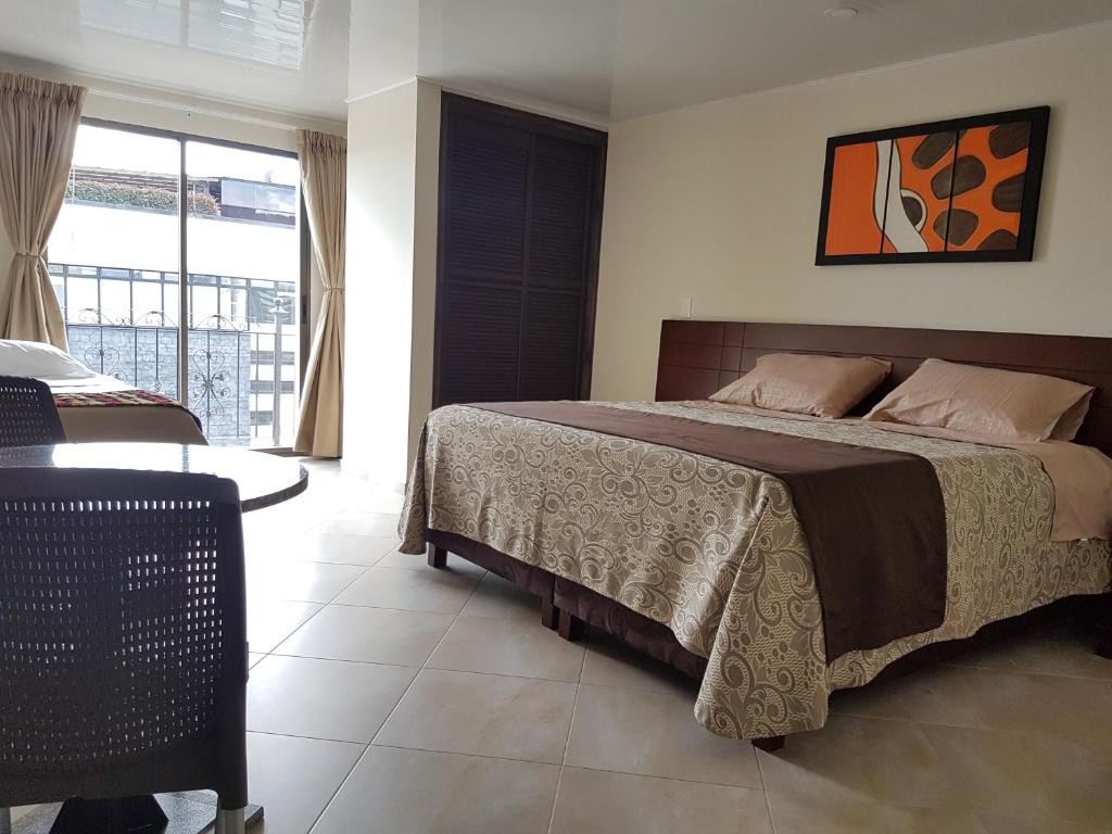 a bedroom with a bed and a table and a window at Hotel Castellana Group in Bogotá