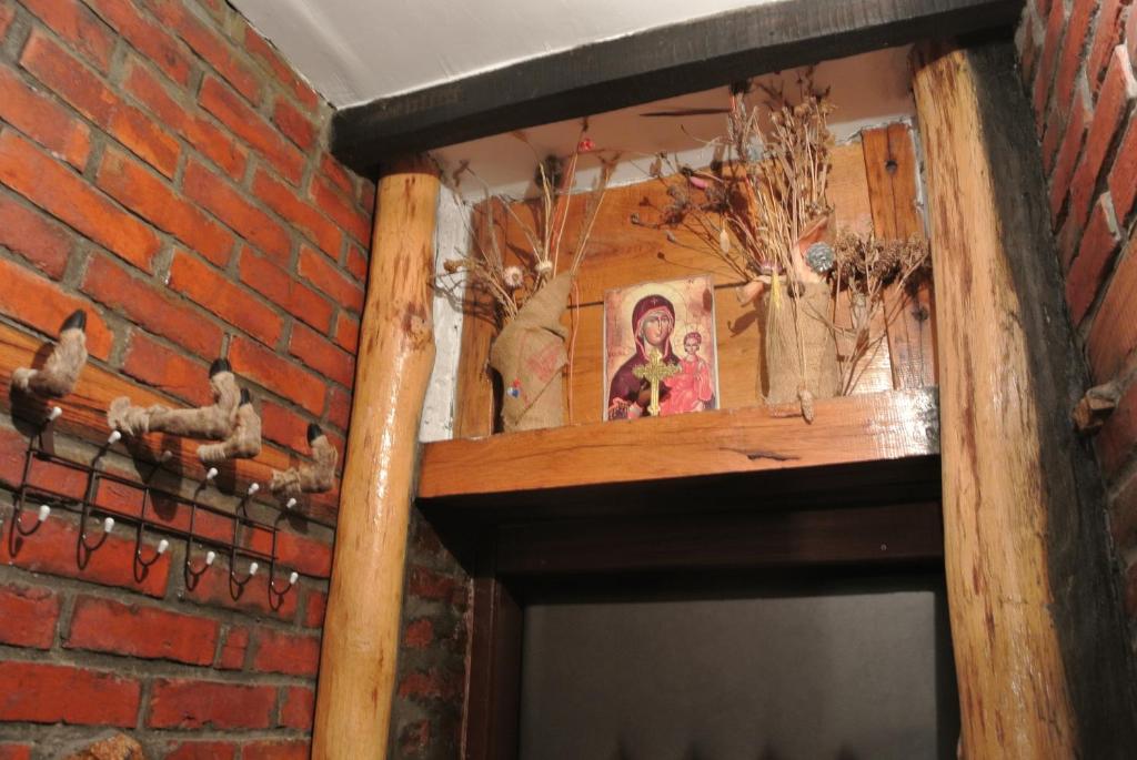 a brick wall with a wooden shelf on a fireplace at Apartmani Mali Raj Rudnik in Rudnik