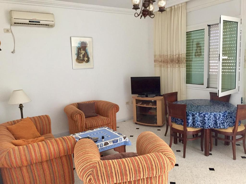 ein Wohnzimmer mit Stühlen, einem Tisch und einem TV in der Unterkunft Maison Dhiefa in Midoun