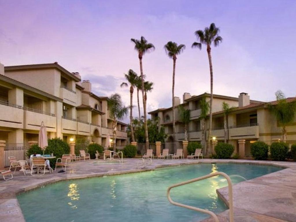 einen Pool in einem Resort mit Stühlen und Palmen in der Unterkunft Poolside Condo to 1 of 3 Resort Pool-Spa Complexes, ALL HEATED & OPEN 24/7/365! in Phoenix