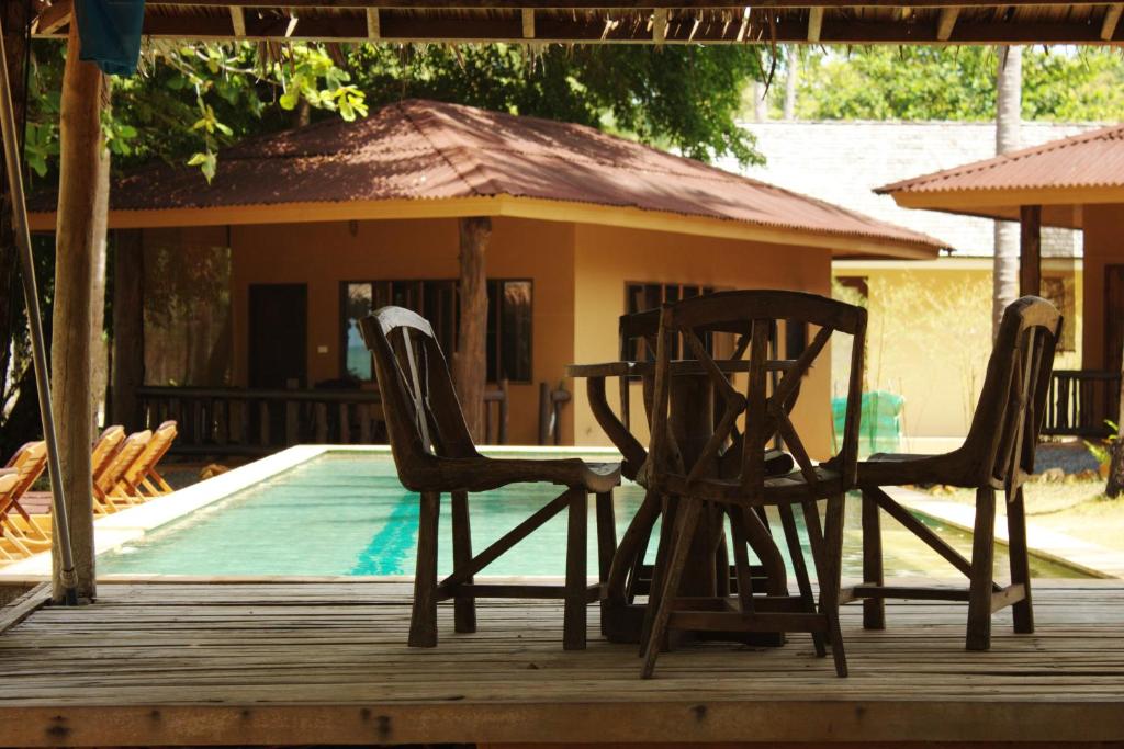 2 sillas y una mesa en una terraza junto a una piscina en Melina Beach Front Bungalows en Tha Lane Bay