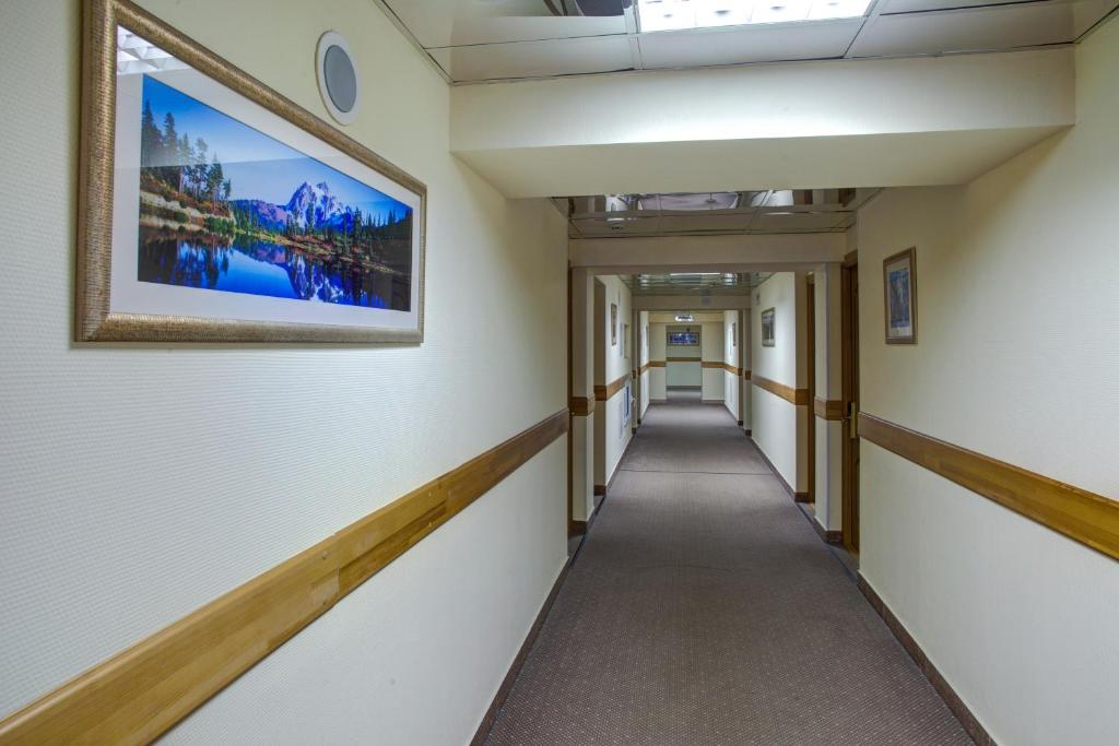 a corridor in an office building with a painting on the wall at AZIMUT Hotel Kemerovo in Kemerovo