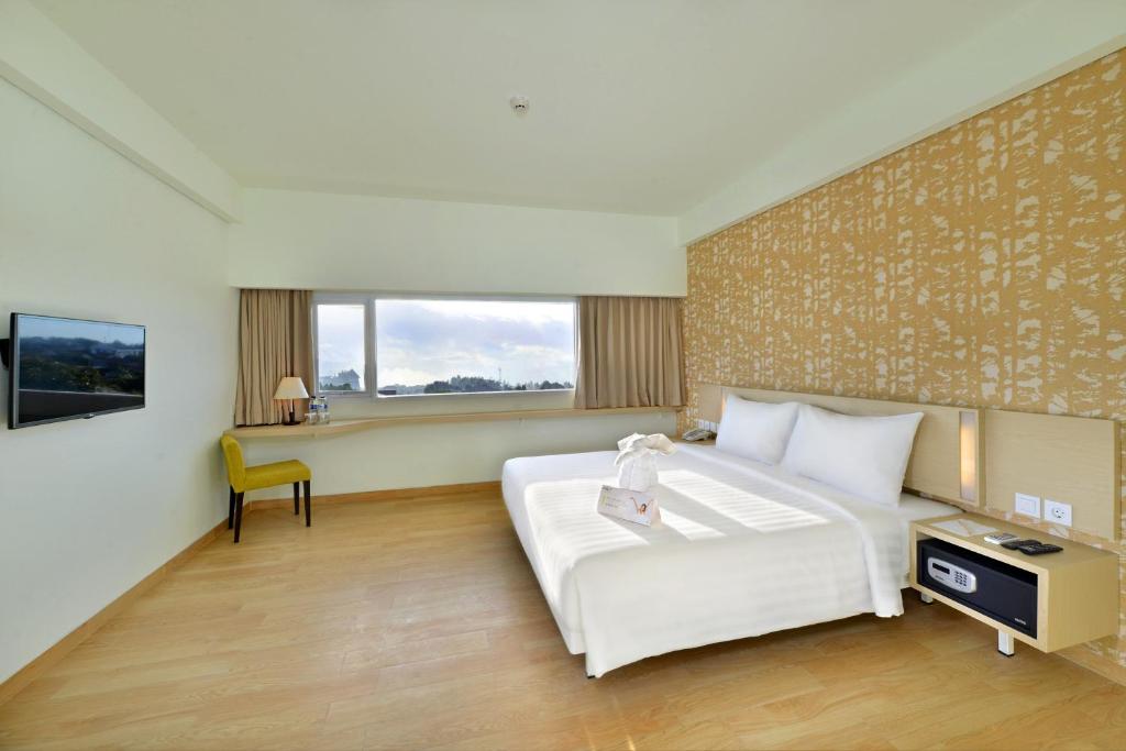 a bedroom with a large white bed and a desk at Whiz Prime Hotel Sudirman Cilacap in Cilacap