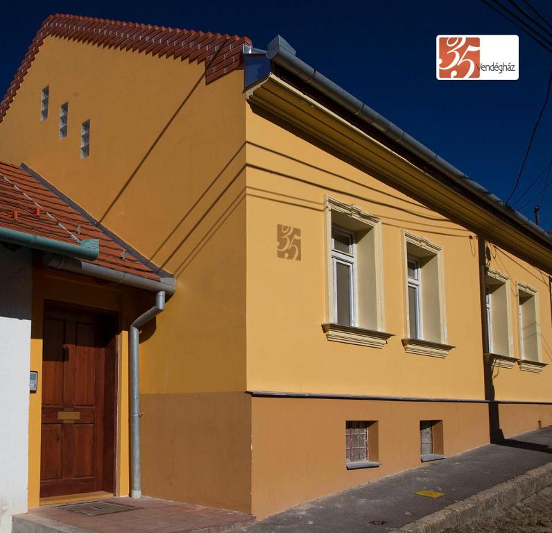 un edificio amarillo con una puerta y dos ventanas en 35 Vendégház Pécs, en Pécs