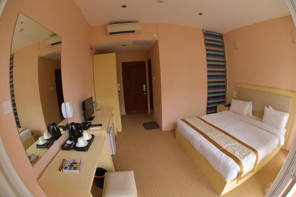 a bedroom with a bed and a desk and a mirror at Grindlays Regency in Ambepussa