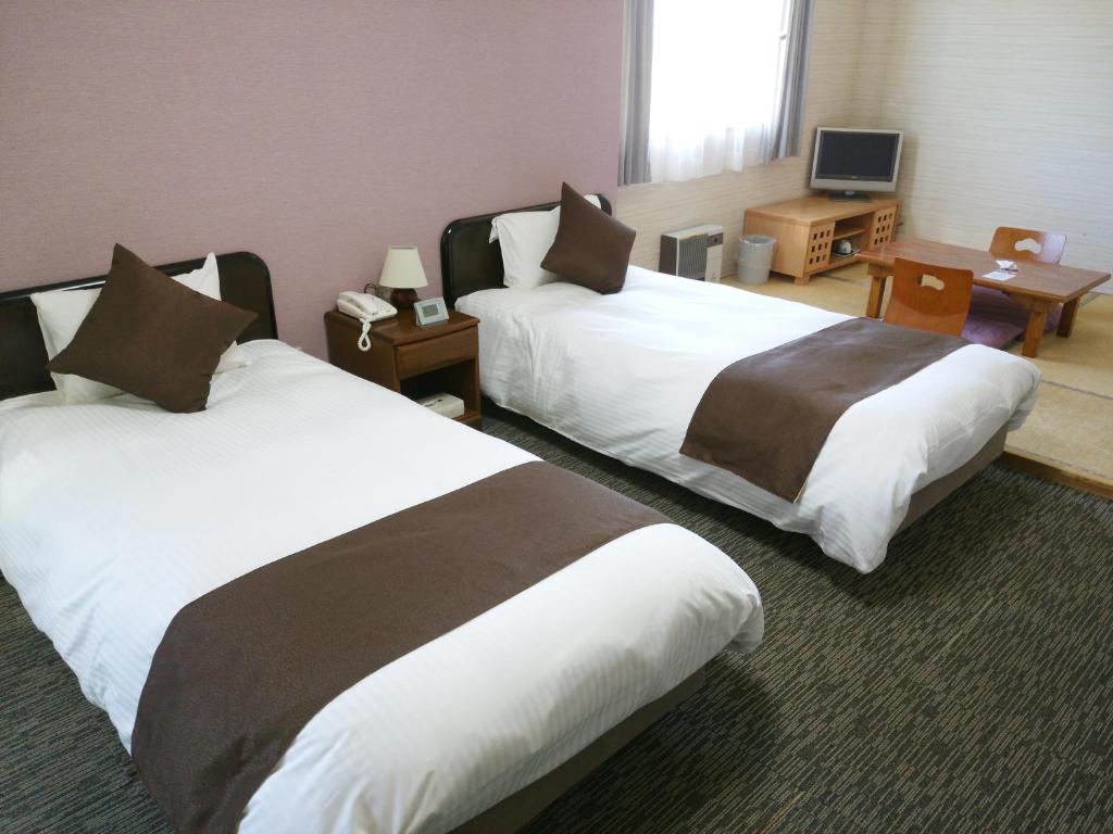 a hotel room with two beds and a television at Resort Inn North Country in Furano