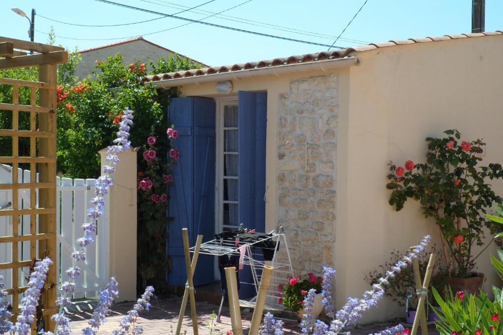uma casa com uma porta azul e algumas flores em Ma Chaumiere Studio em Saint-Pierre-dʼOléron