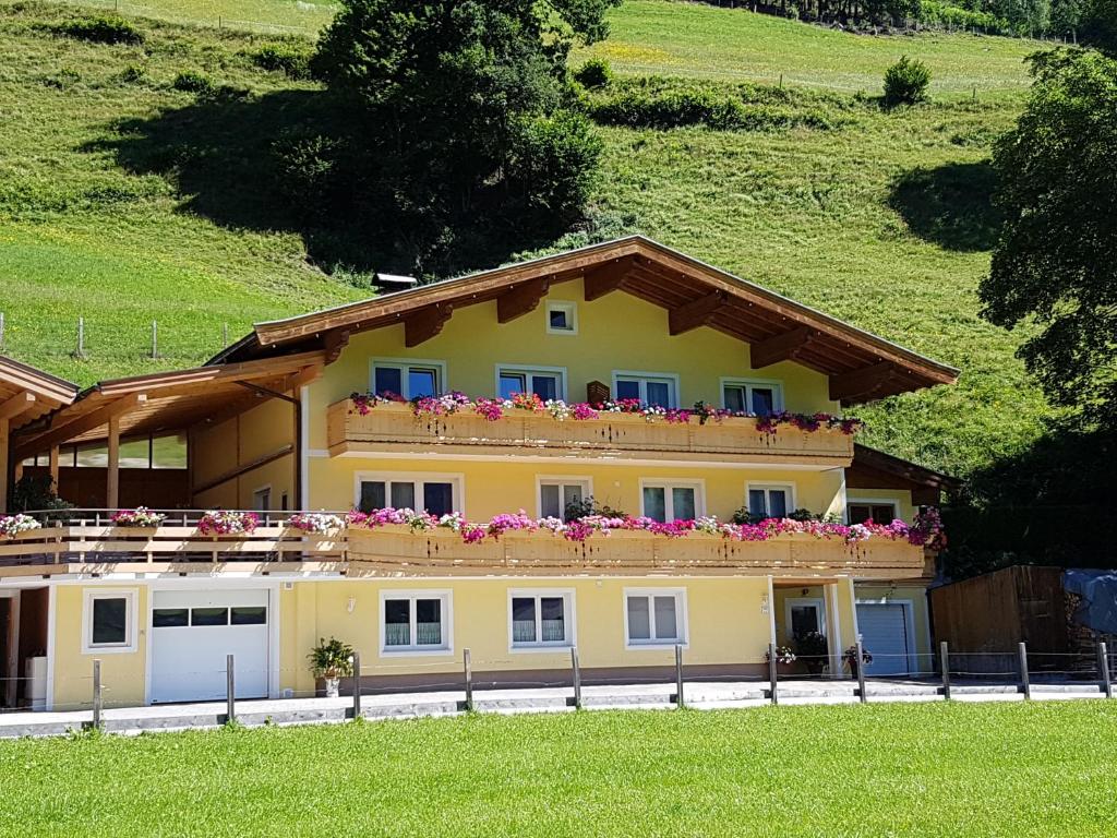 a yellow house with flowers on the top of it at Haus Steger in Stuhlfelden