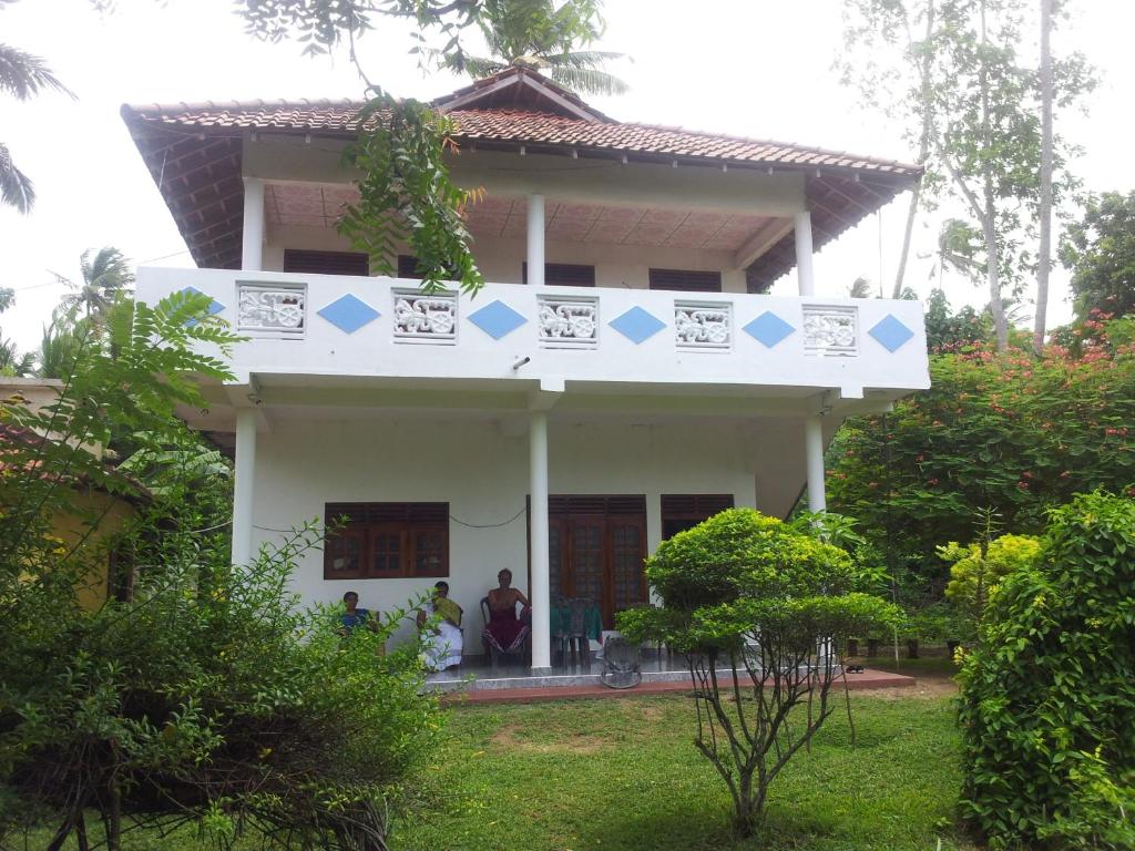 a white house with blue arrows on it at Malika Homestay in Midigama