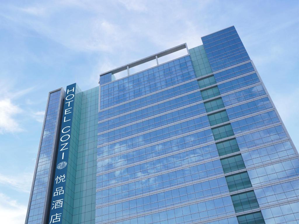 un edificio di alto vetro con un cielo blu sullo sfondo di Hotel COZi Wetland a Hong Kong