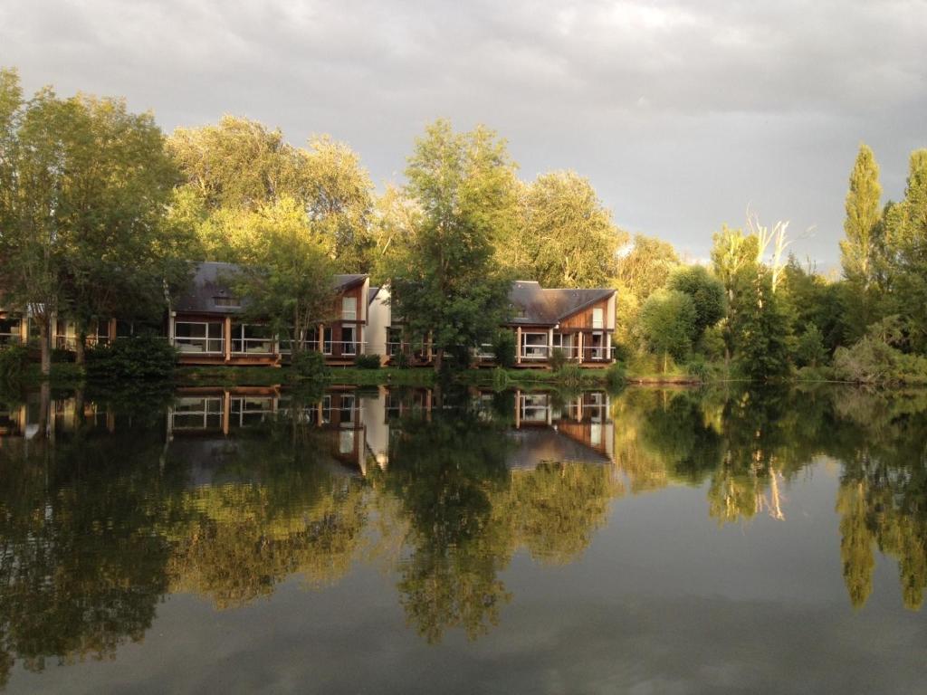 una casa en un lago con su reflejo en el agua en Hôtel L'ile Du Saussay, en Itteville
