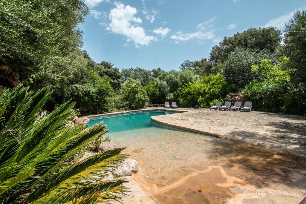 a swimming pool in a yard with chairs and trees at Villa Es Sestadors By homevillas360 in Búger