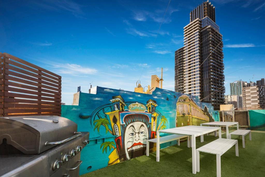 a building with tables and a mural on it at Nate's Place Backpackers Melbourne in Melbourne