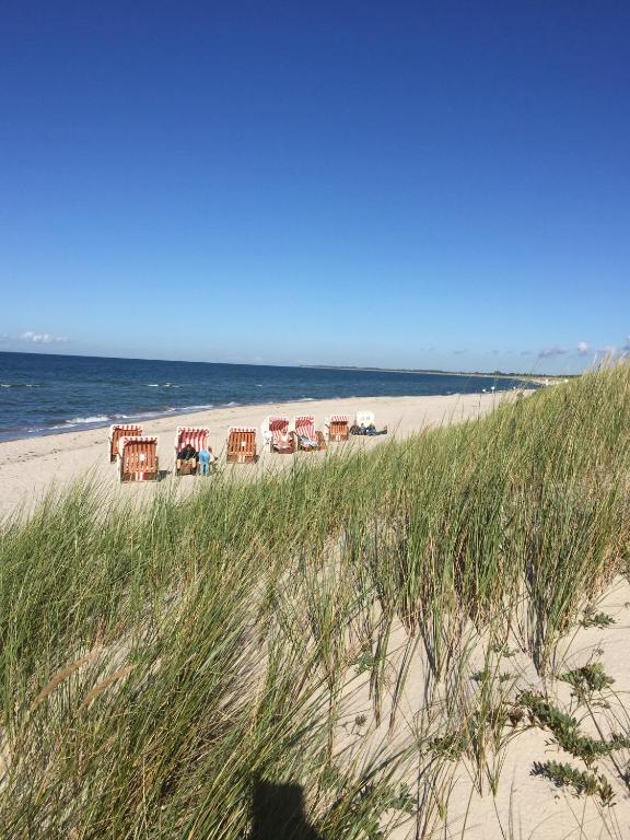 a beach with chairs and tables and the ocean at Ferienhaus Dierhagen Strand I & II in Dierhagen