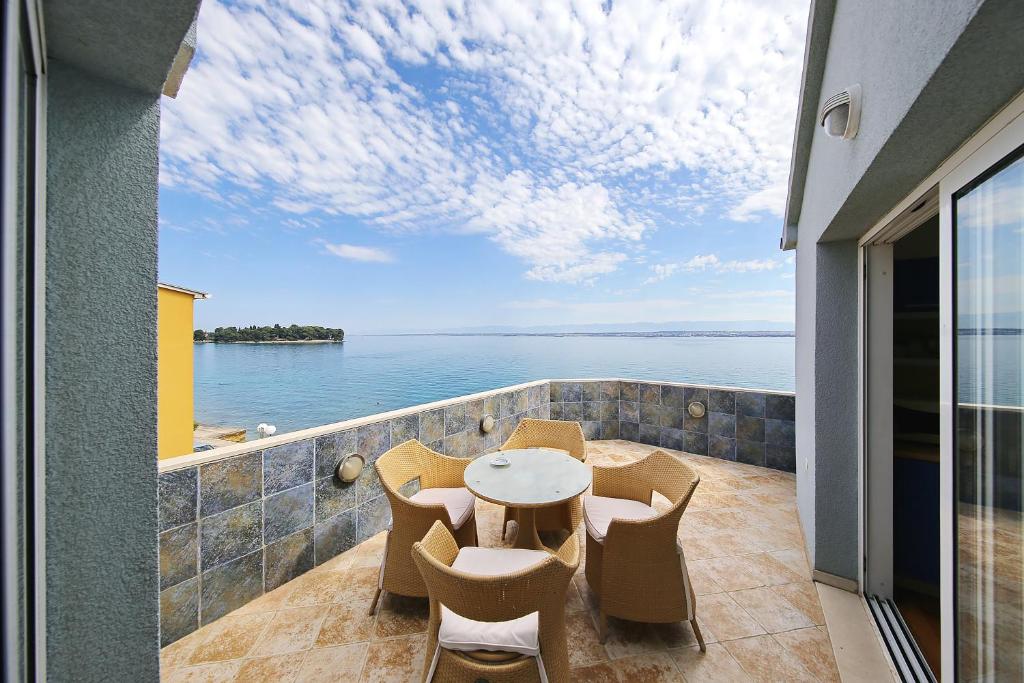 balcón con mesa, sillas y vistas al agua en Punta Preko Apartments en Preko
