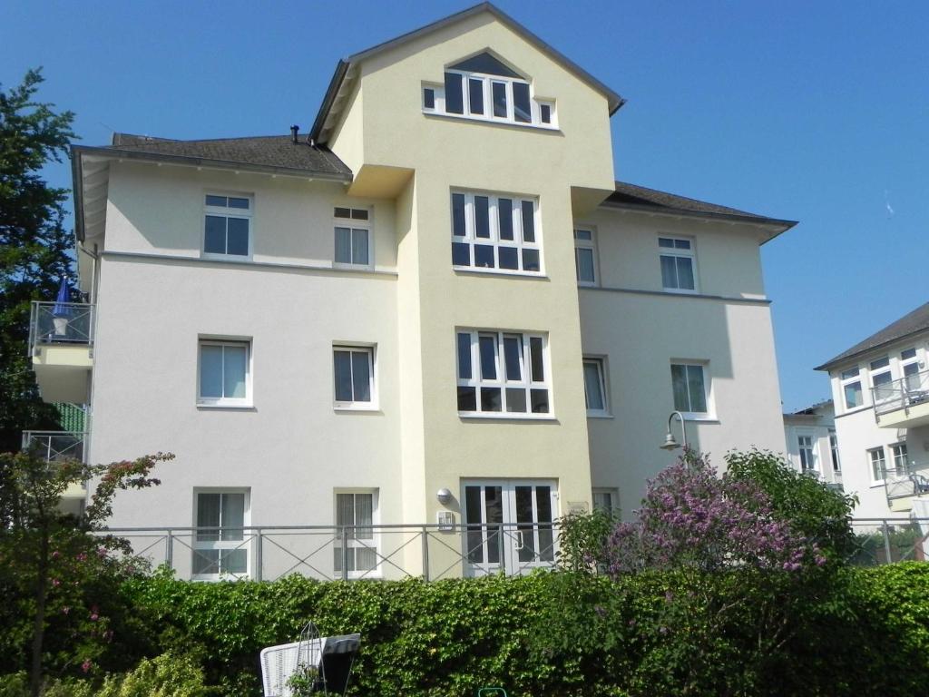 ein hohes weißes Gebäude mit einem Dach in der Unterkunft Ferienwohnung 3 26 Inselstrand in Ahlbeck