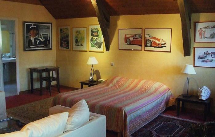 a living room with a bed, couch and a painting on the wall at Le Relais des Arcandiers in Lohéac
