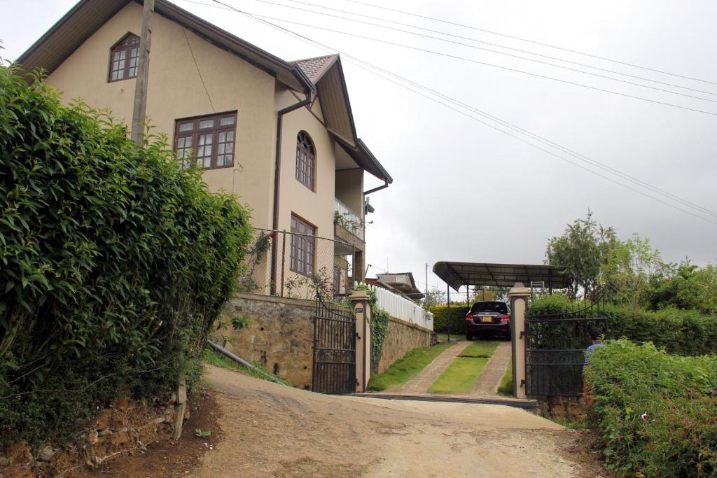 a house with a gate on a dirt road at Perera Homestay in Nuwara Eliya