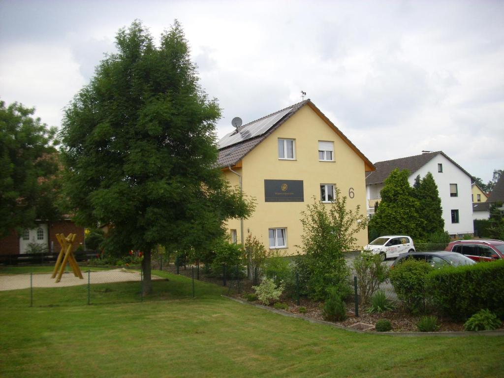 ein gelbes Haus mit einem Baum im Hof in der Unterkunft Penny Pension in Wolfsburg