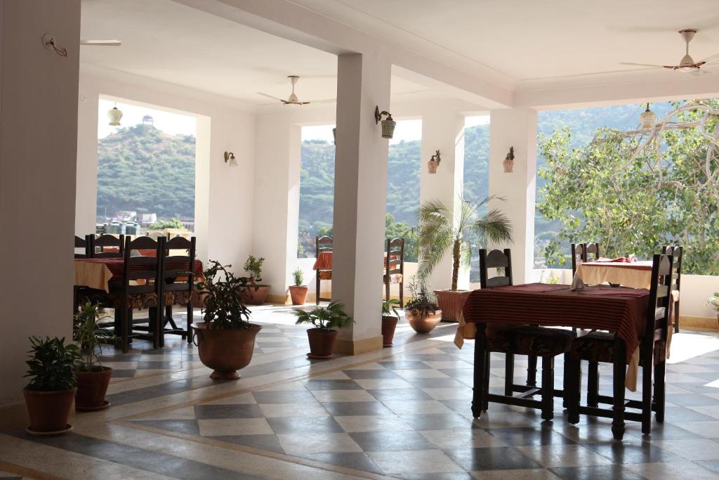 un comedor con mesas, sillas y ventanas en Haveli Katkoun, en Bundi