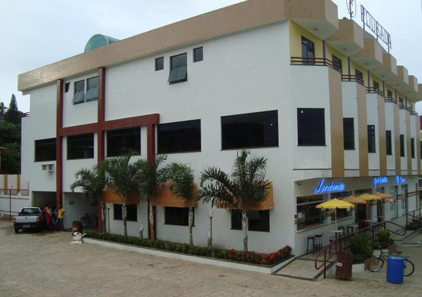 a large white building with palm trees in front of it at Pousada Cardoso in Ipiaú