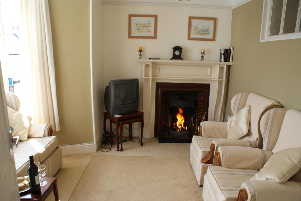 a living room with a fireplace and a tv at Scenery Cottage in Bridford