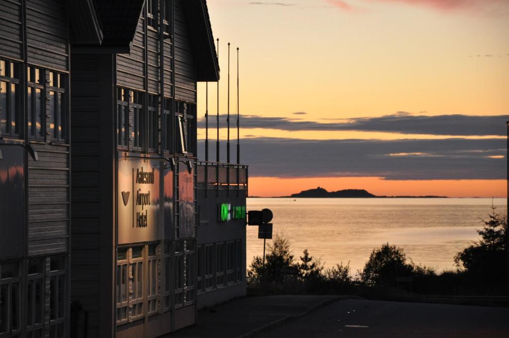 ein Gebäude mit Blick auf den Ozean bei Sonnenuntergang in der Unterkunft Aalesund Airport Hotel in Ytterland