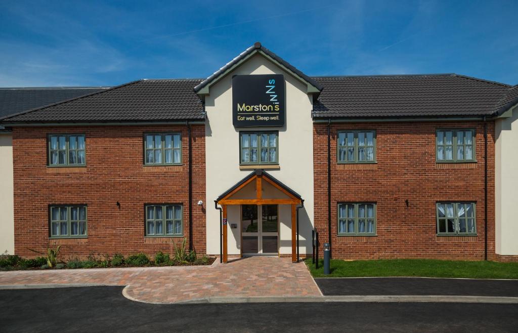 a large brick building with a sign in front of it at Spread Eagle, Gailey by Marston's Inns in Gailey