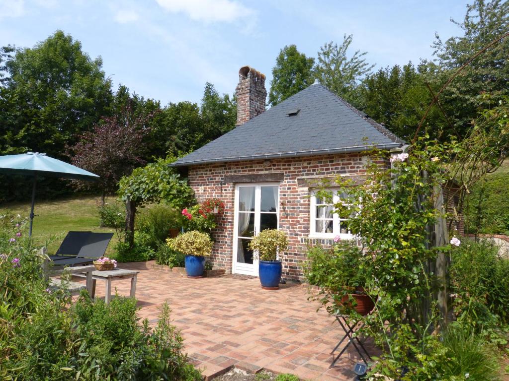 a brick house with a patio in a garden at Gîte de Charme Les Petits Matins Bleus in Sainte-Marguerite-de-Viette