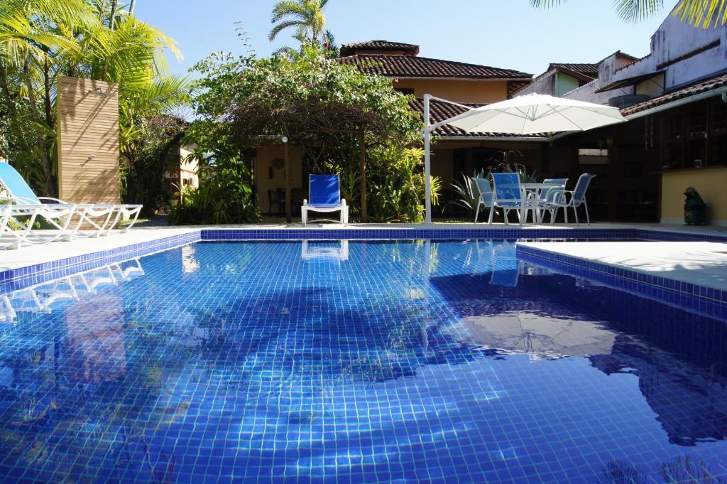 una piscina azul con sillas y una casa en Pousada Paisagem, en Paraty