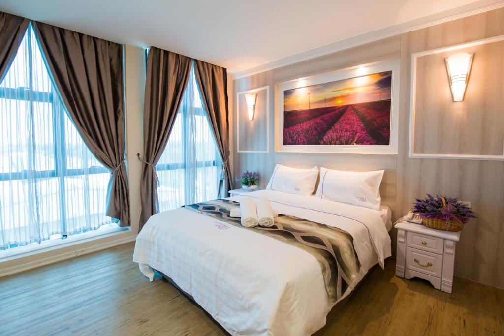 1 dormitorio con 1 cama blanca grande y ventanas en Lavender Inn USJ en Subang Jaya