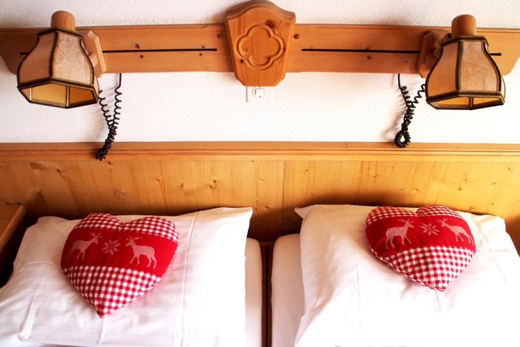 twee rode en witte kussens op een bed met twee lichten bij Alpenhof in Grindelwald