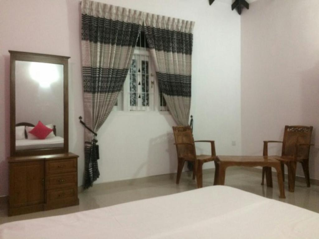 a bedroom with a bed and a mirror and chairs at Ahasna Family Villa in Negombo