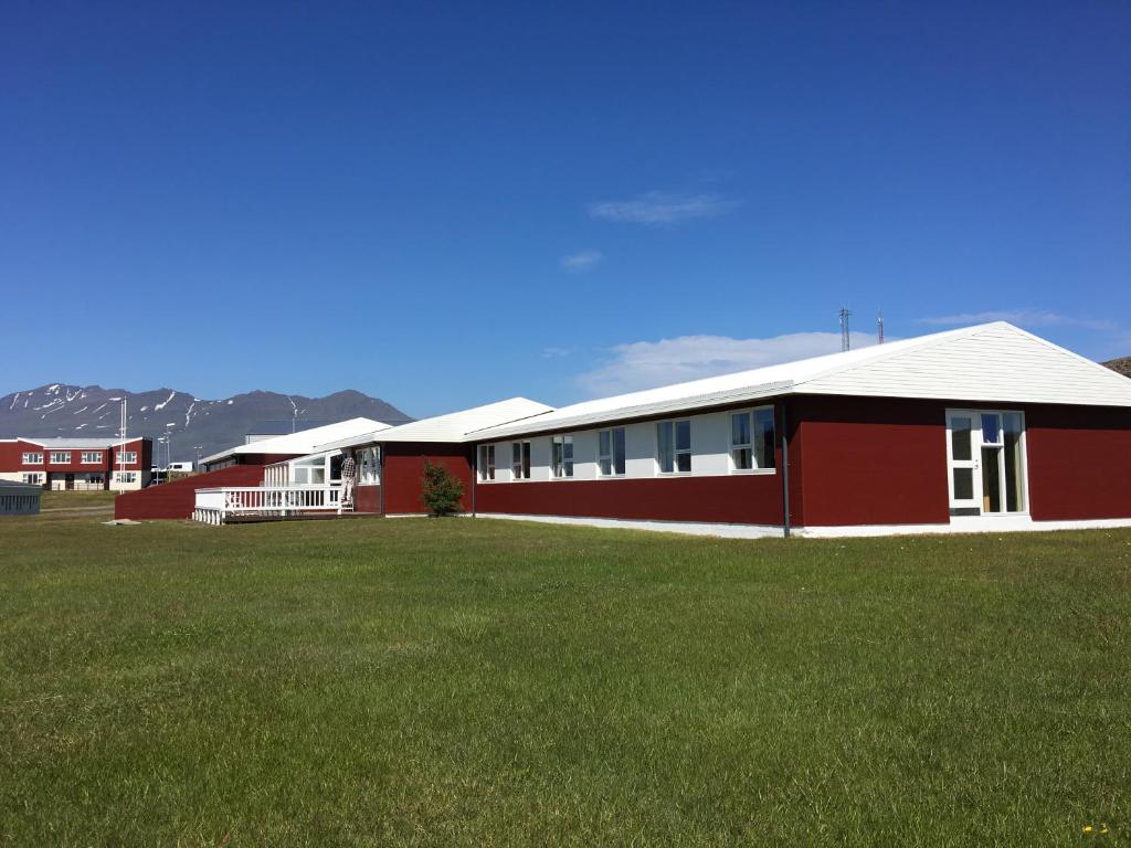 een rood gebouw met een grasveld ervoor bij Helgafell Hostel in Djúpivogur