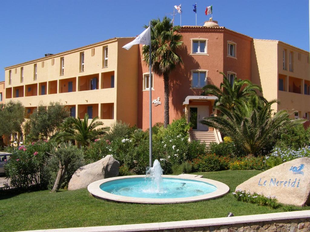 einen Brunnen im Gras vor einem Gebäude in der Unterkunft Le Nereidi Hotel Residence in La Maddalena