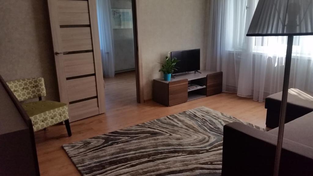 a living room with a television and a room with a couch at Apartment on Brivzemnieka in Liepāja