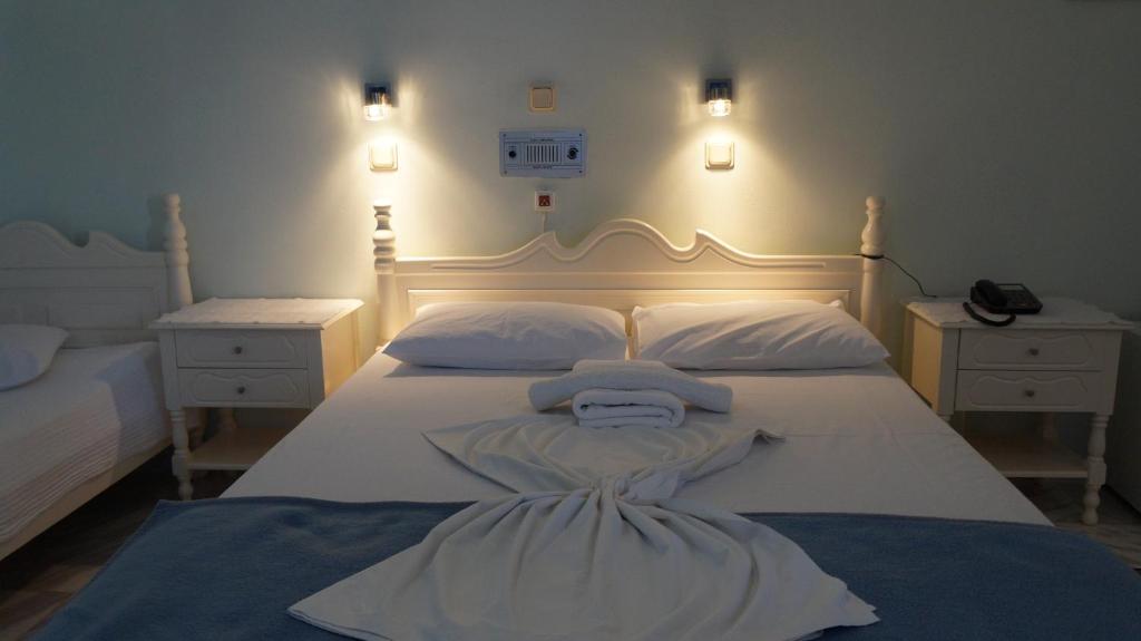 ein Schlafzimmer mit einem weißen Bett und zwei Nachttischen in der Unterkunft Amanda Hotel in Karlovasi