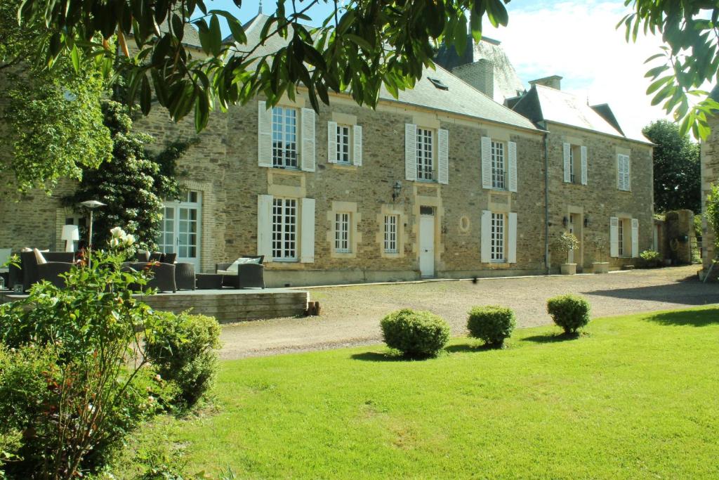 Manoir de la Queue Du Renard في Tracy-Bocage: مبنى من الطوب كبير مع ساحة عشب