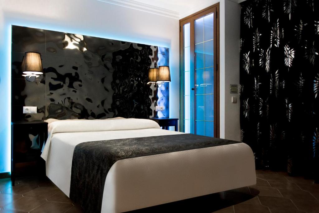 a bedroom with a large white bed with a black wall at Hostal Alhambra - Adults Only in Nerja