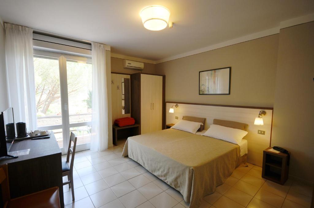 1 dormitorio con cama, escritorio y ventana en Hotel Primavera, en Barberino di Val d'Elsa