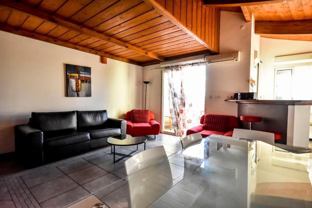 - un salon avec un canapé noir et des fauteuils rouges dans l'établissement Entre plage et ville, à Saint-Gilles les Bains