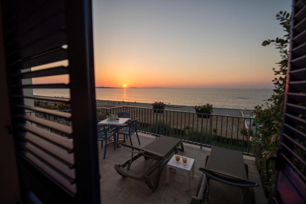 un balcón con vistas al océano al atardecer en Karma Resort, en Venetico