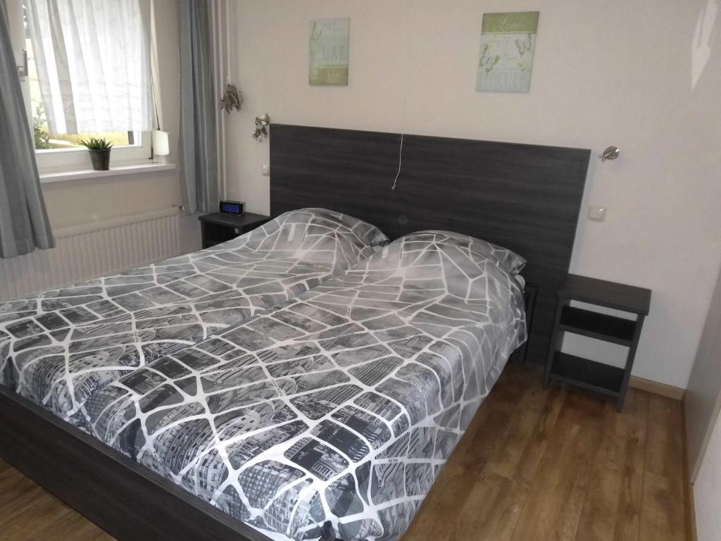 uma cama com um edredão preto e branco num quarto em Welca em Baarlo