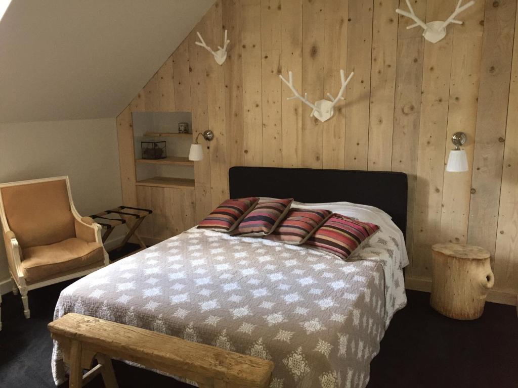 a bedroom with a bed and a chair andanimal heads on the wall at B&B Fleurie in Saint-Amand-Montrond