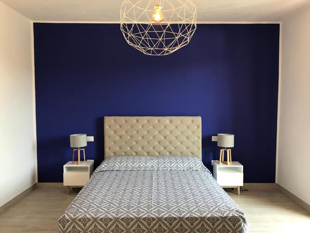 a blue bedroom with a bed and a blue wall at Safran in Villasimius