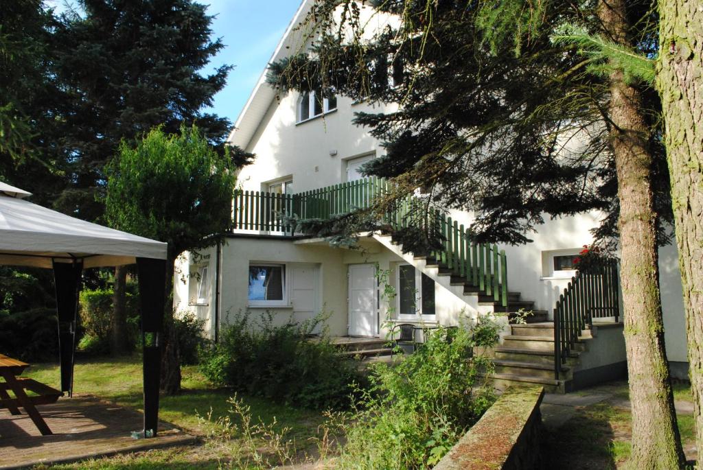 Casa blanca con barandillas verdes y escaleras en Pokoje goscinne Jaskolcze Gniazdo, en Dziwnówek