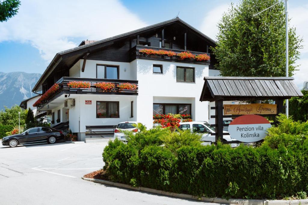 a building with cars parked in a parking lot at Hotel GH Kolinska -Adults Only- in Bled