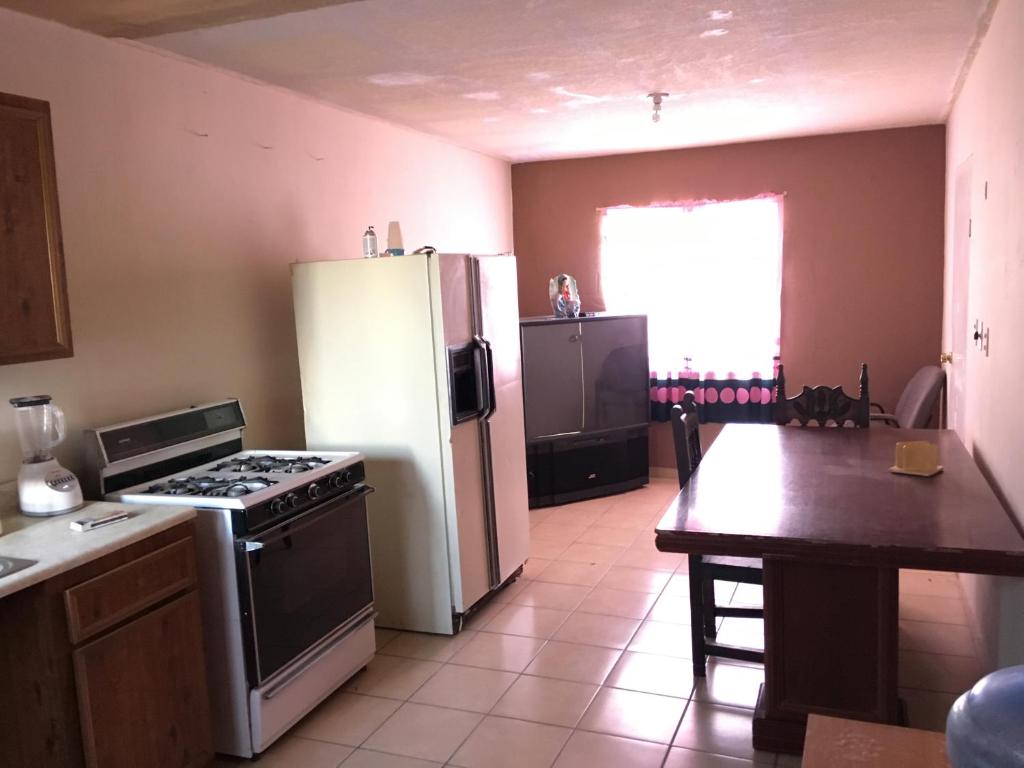 uma cozinha com um fogão, um frigorífico e uma mesa em Blanquita guesthouse em Manuel F. Martínez