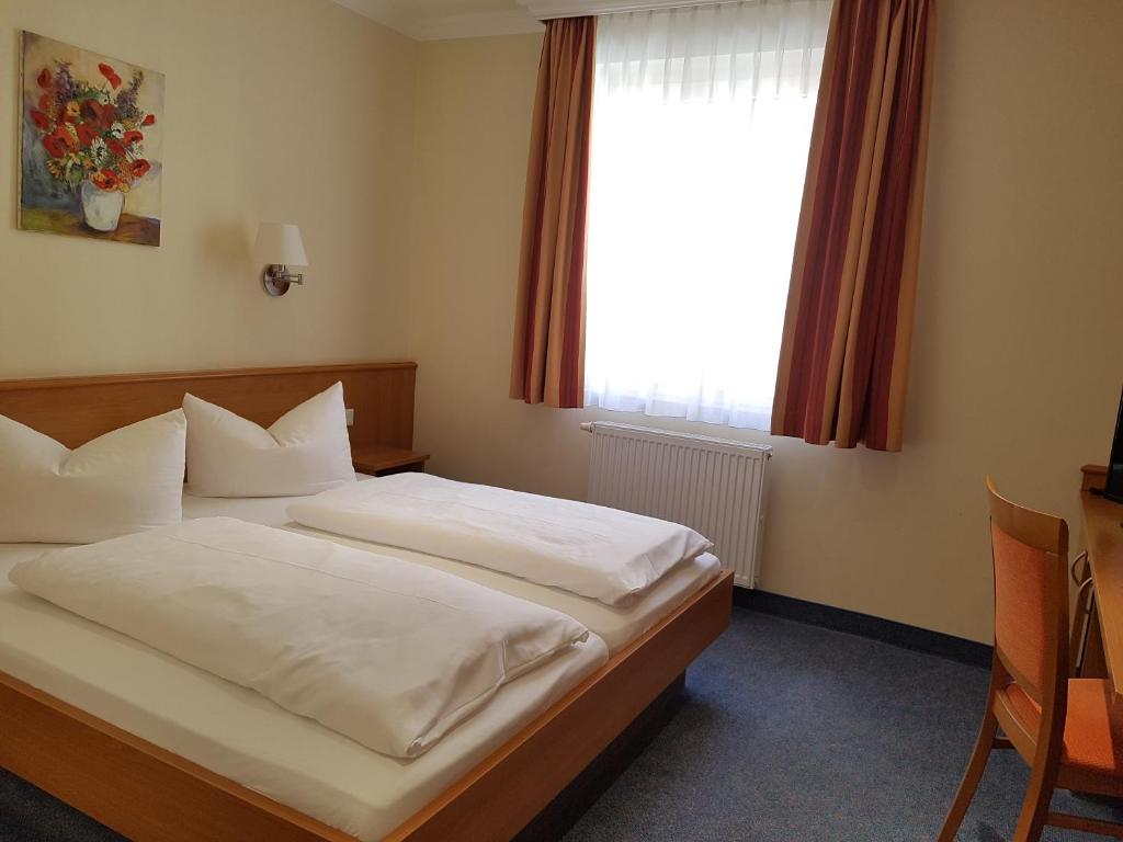 a bedroom with a bed with white sheets and a window at Hotel Garni Keiml in Nuremberg